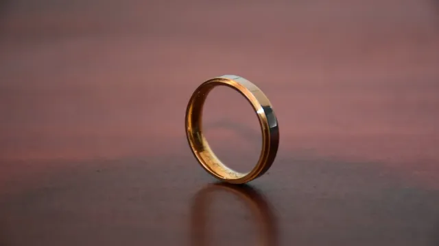 Goldener Ehering auf einem dunklen Holztisch – Seitensprung-Portale im Vergleich