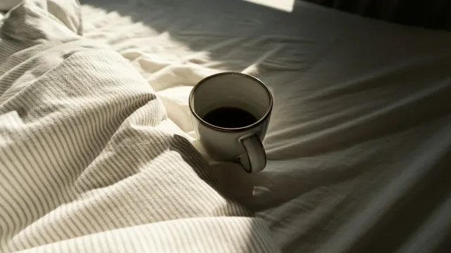 Kaffeetasse auf zerwühlter weißer Bettwäsche im Morgenlicht – Freundschaft Plus mit klaren Regeln
