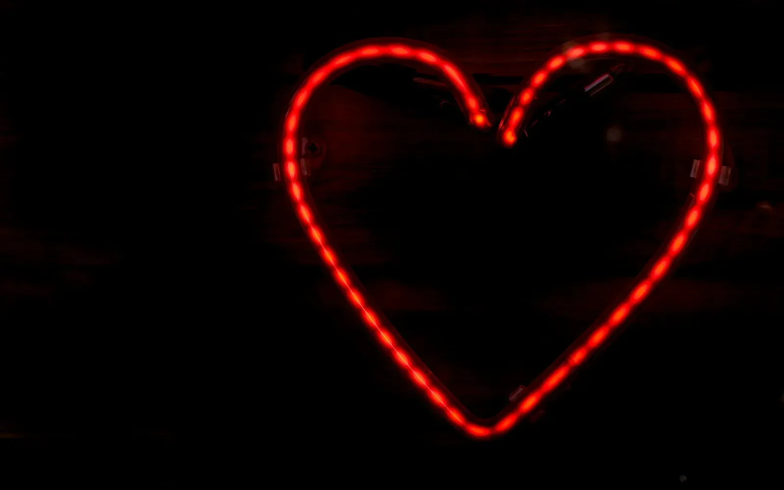 Leuchtendes rotes Neon-Herz vor dunklem Hintergrund