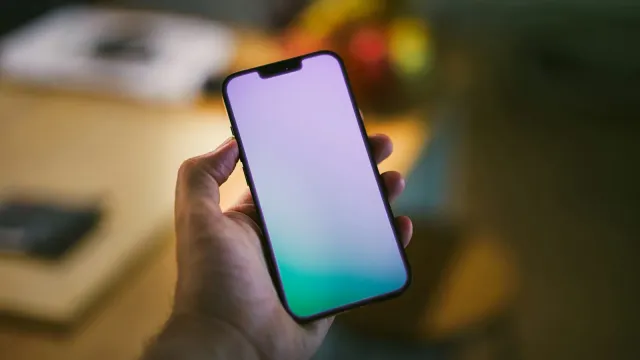Hand hält ein leuchtendes Smartphone im gedämpften Abendlicht – Sexting Tipps