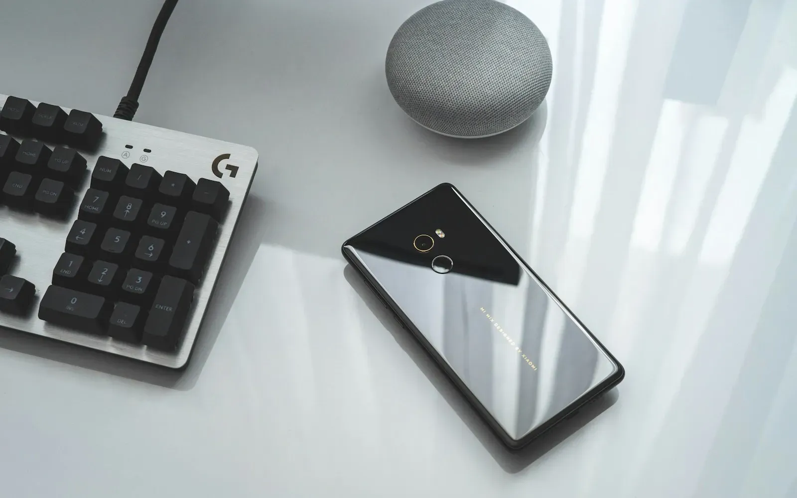 Smartphone liegt neben einer Tastatur auf einem hellen Schreibtisch