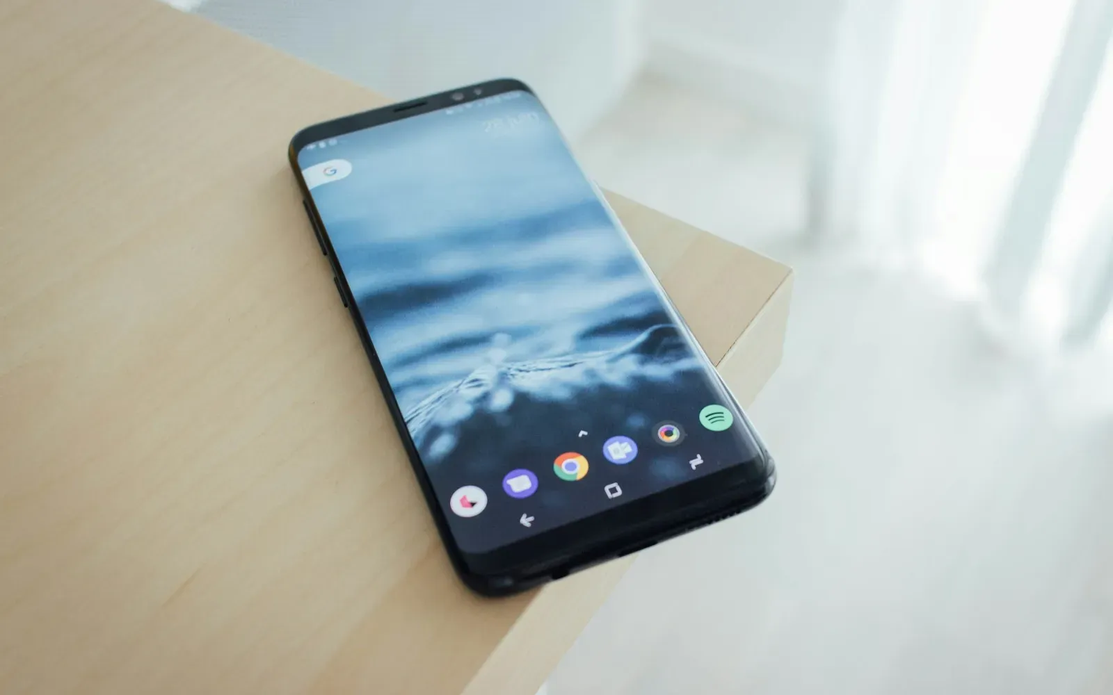 Smartphone liegt auf einem hellen Holztisch