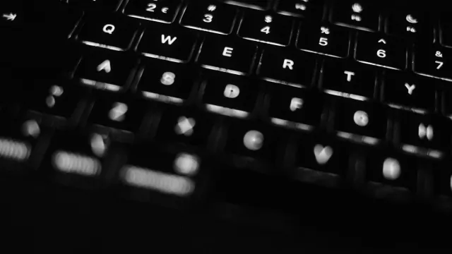 Beleuchtete Laptop-Tastatur in einem dunklen Raum – Huren Test Forum und Freierforen erklärt